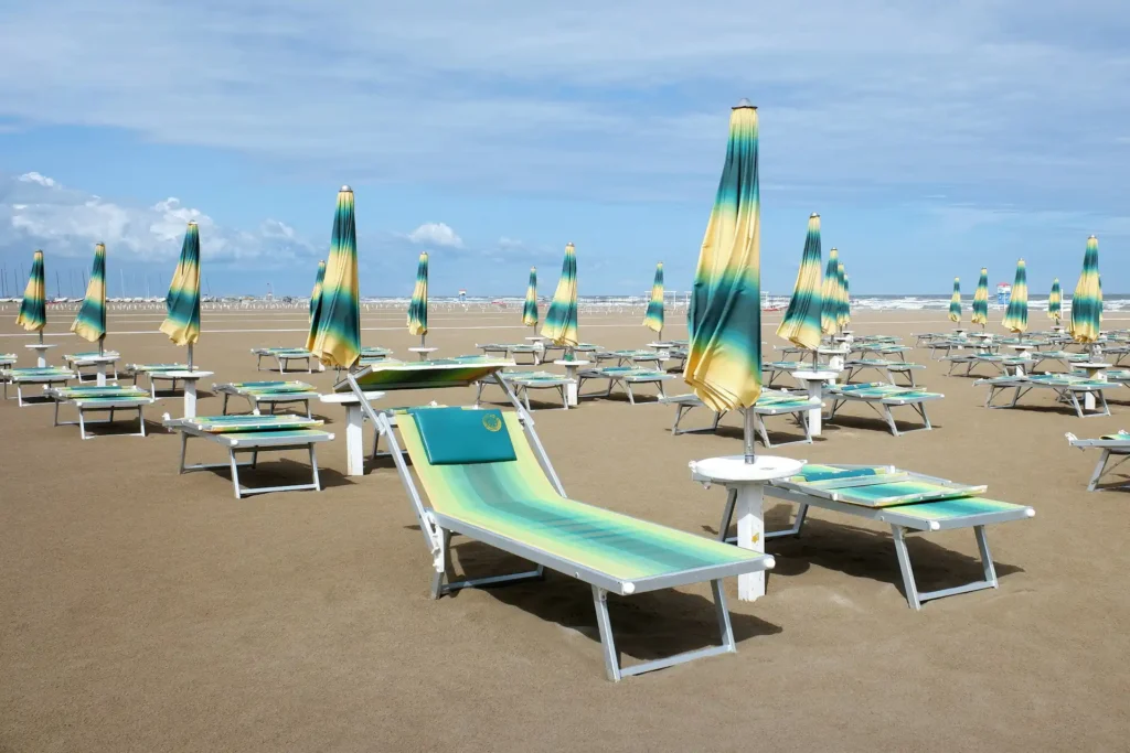 Nell'immagine, la panoramica di una spiaggia con lettini e ombrelloni chiusi di colore giallo e verde.
